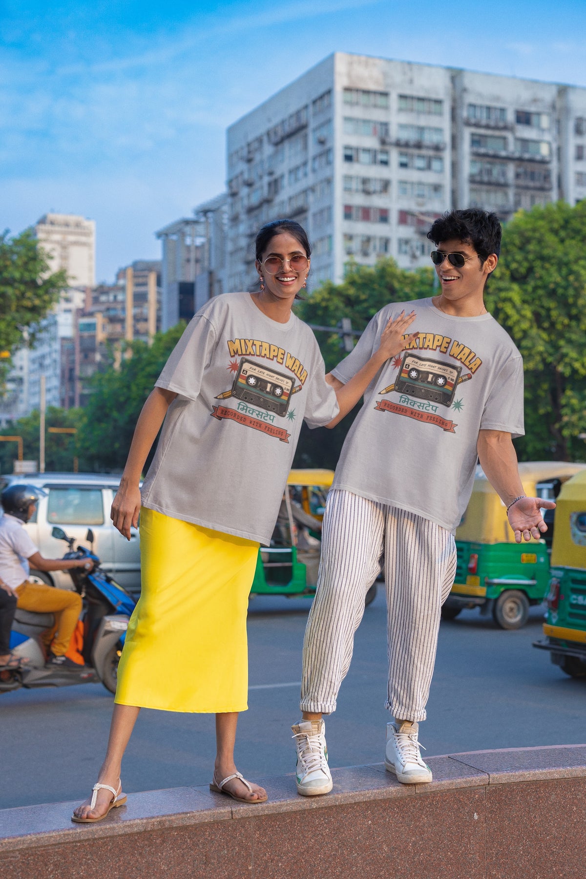 Man and woman wearing the Melange Grey Mixtape Wala oversized t-shirt on a city street with auto-rickshaws