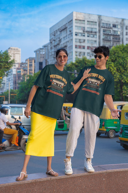 Man and woman wearing the Petrol Blue Mixtape Wala oversized t-shirt on a city street with auto-rickshaws