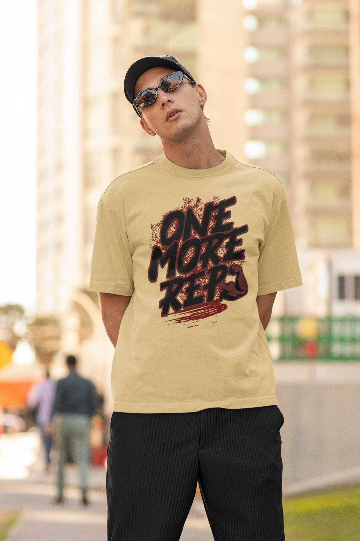 Model wearing the Nauma One More Rep gym graphic unisex oversized T-shirt in beige on a city street