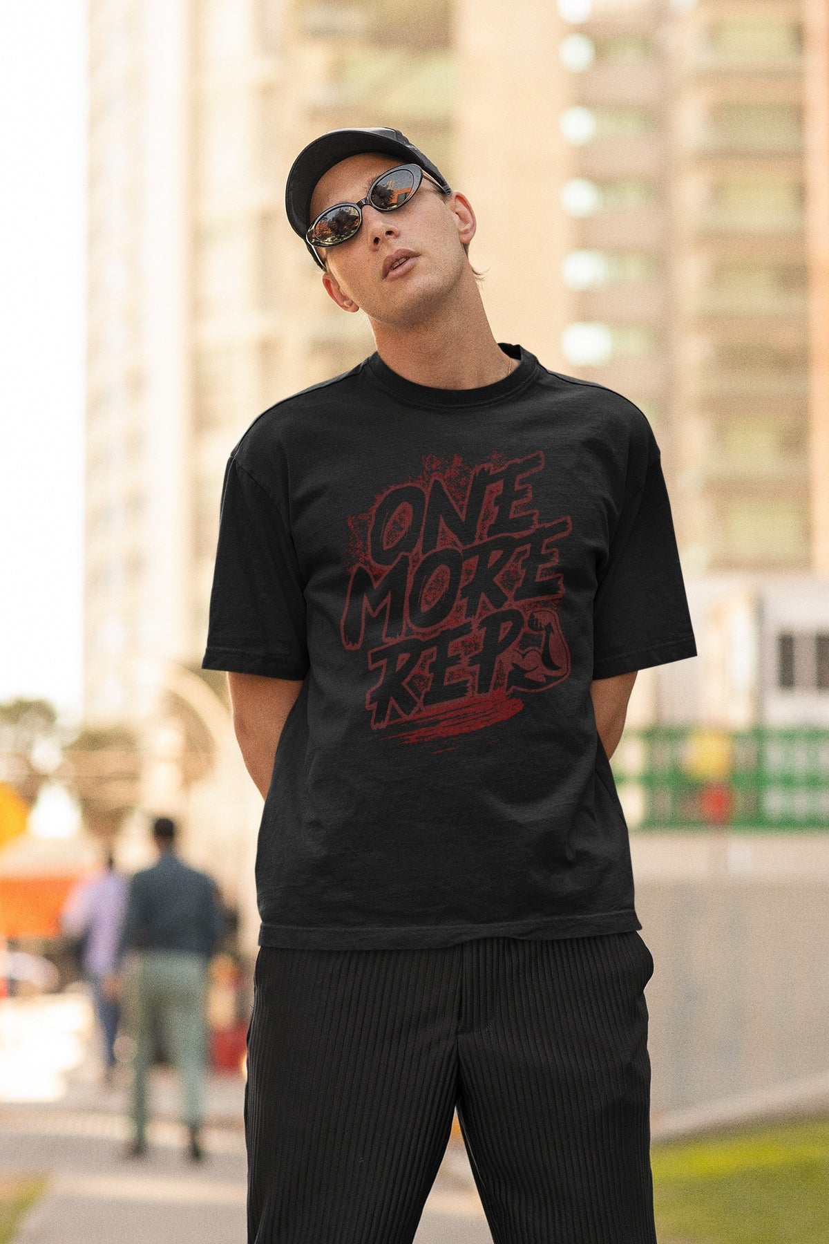 Model wearing the Nauma One More Rep gym graphic unisex oversized T-shirt in black on a city street