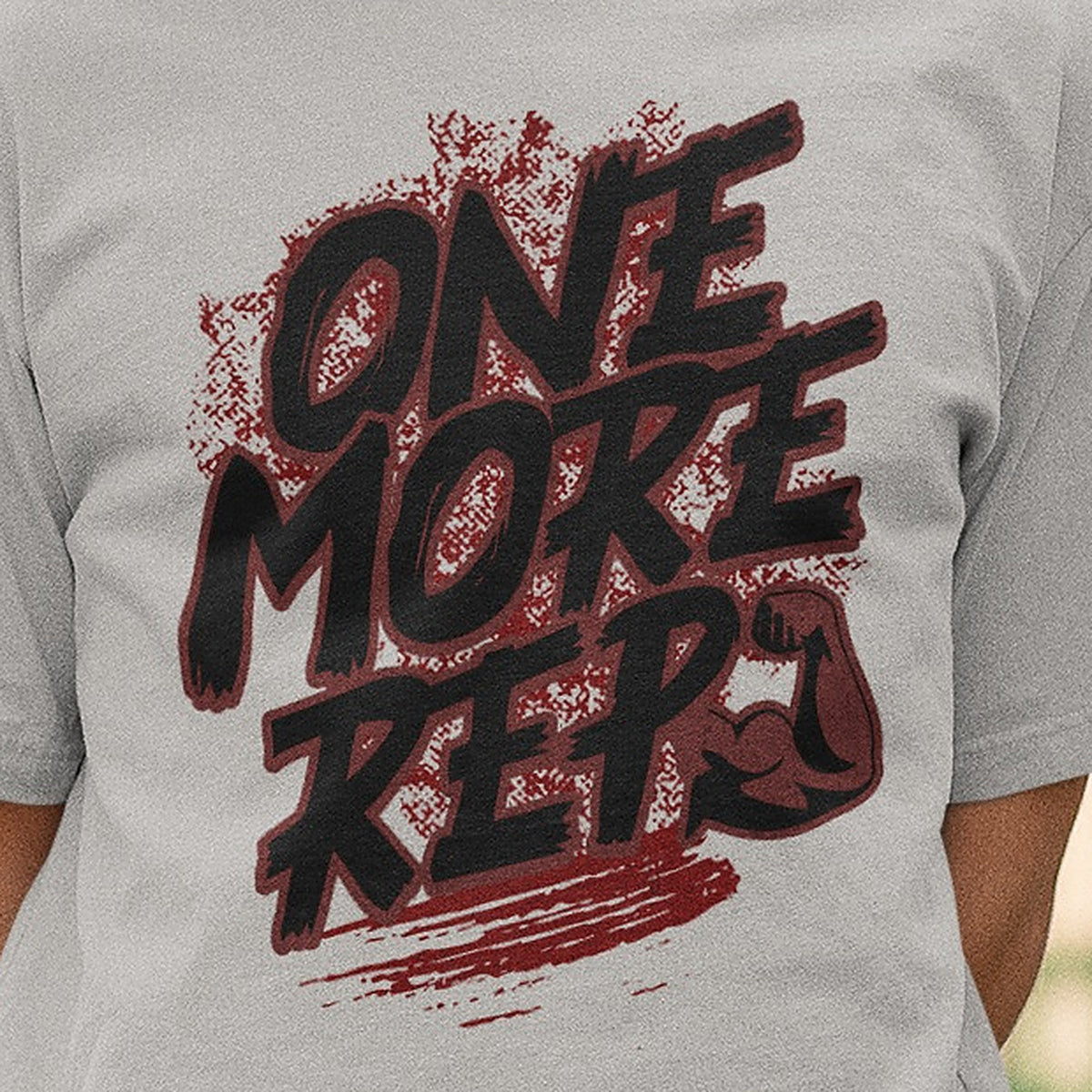 Close-up of the One More Rep brush lettering and flexed arm print on the melange grey Nauma oversized T-shirt