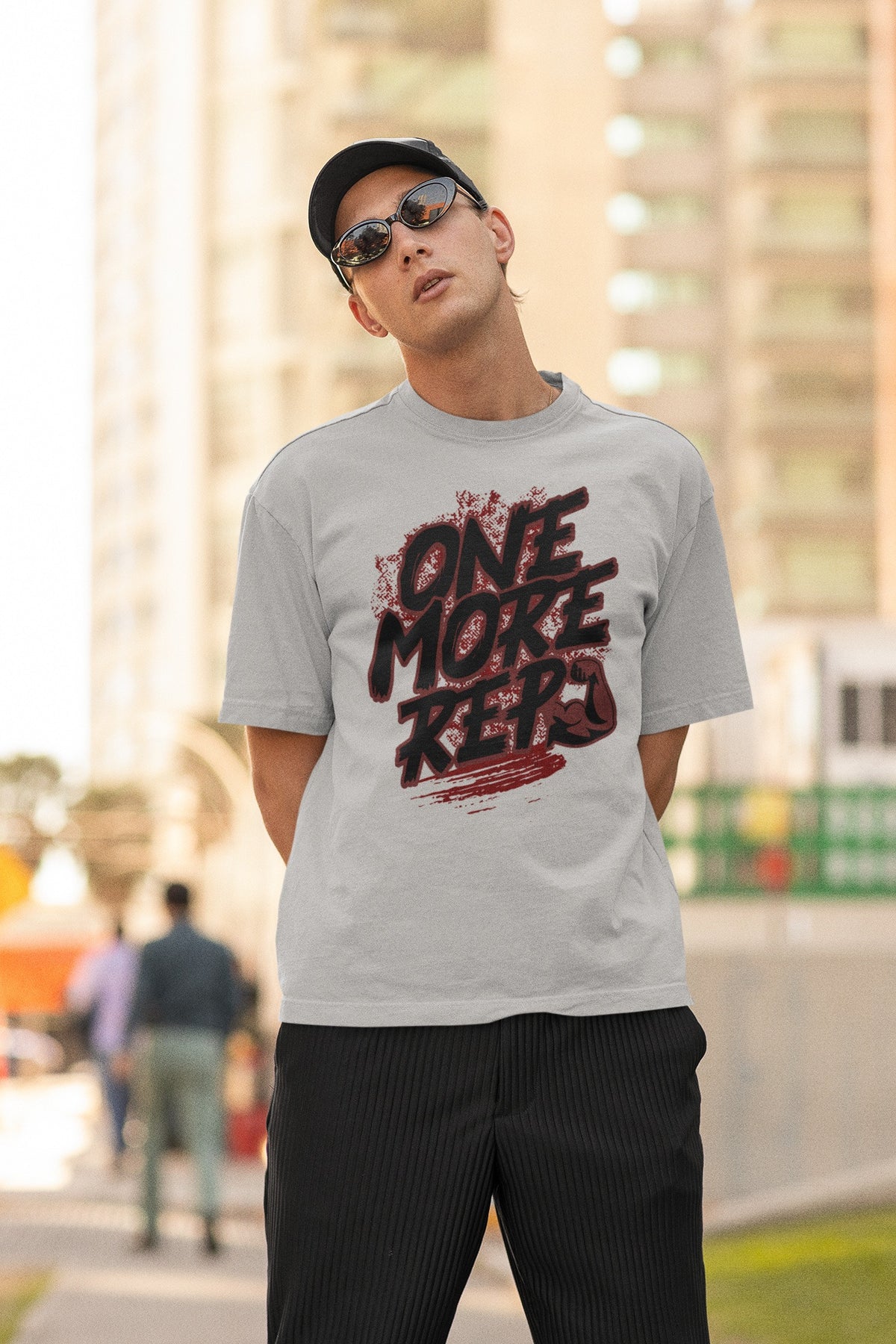 Model wearing the Nauma One More Rep gym graphic unisex oversized T-shirt in melange grey on a city street