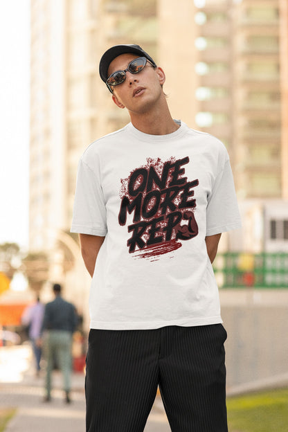 Model wearing the Nauma One More Rep gym graphic unisex oversized T-shirt in white on a city street