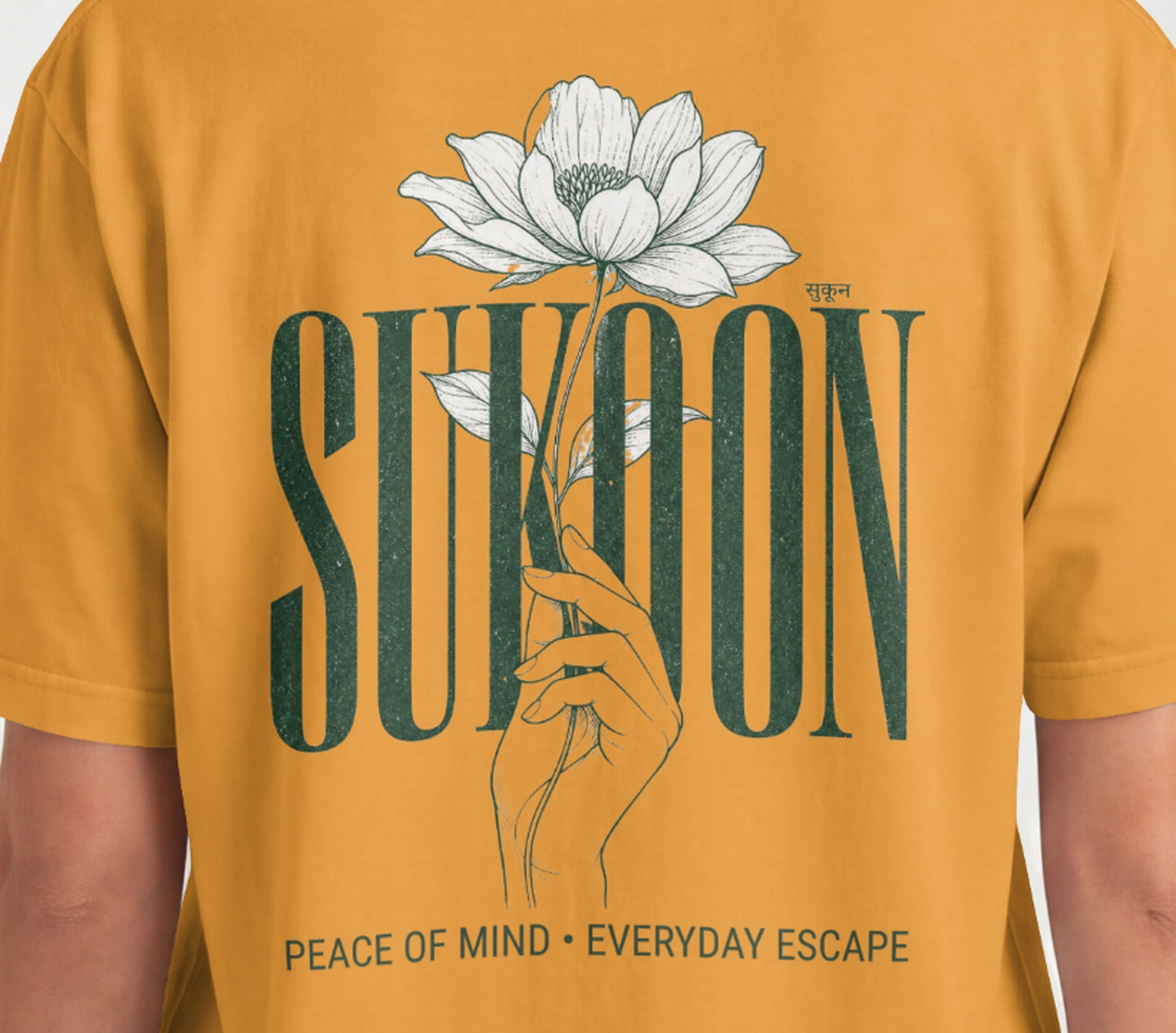 Closeup of Nauma Sukoon oversized t-shirt back print in golden yellow with lotus flower and hand illustration