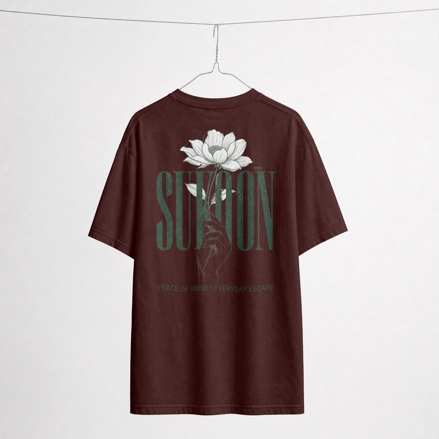 Nauma Sukoon oversized t-shirt in maroon on a hanger, back print with lotus flower and hand illustration