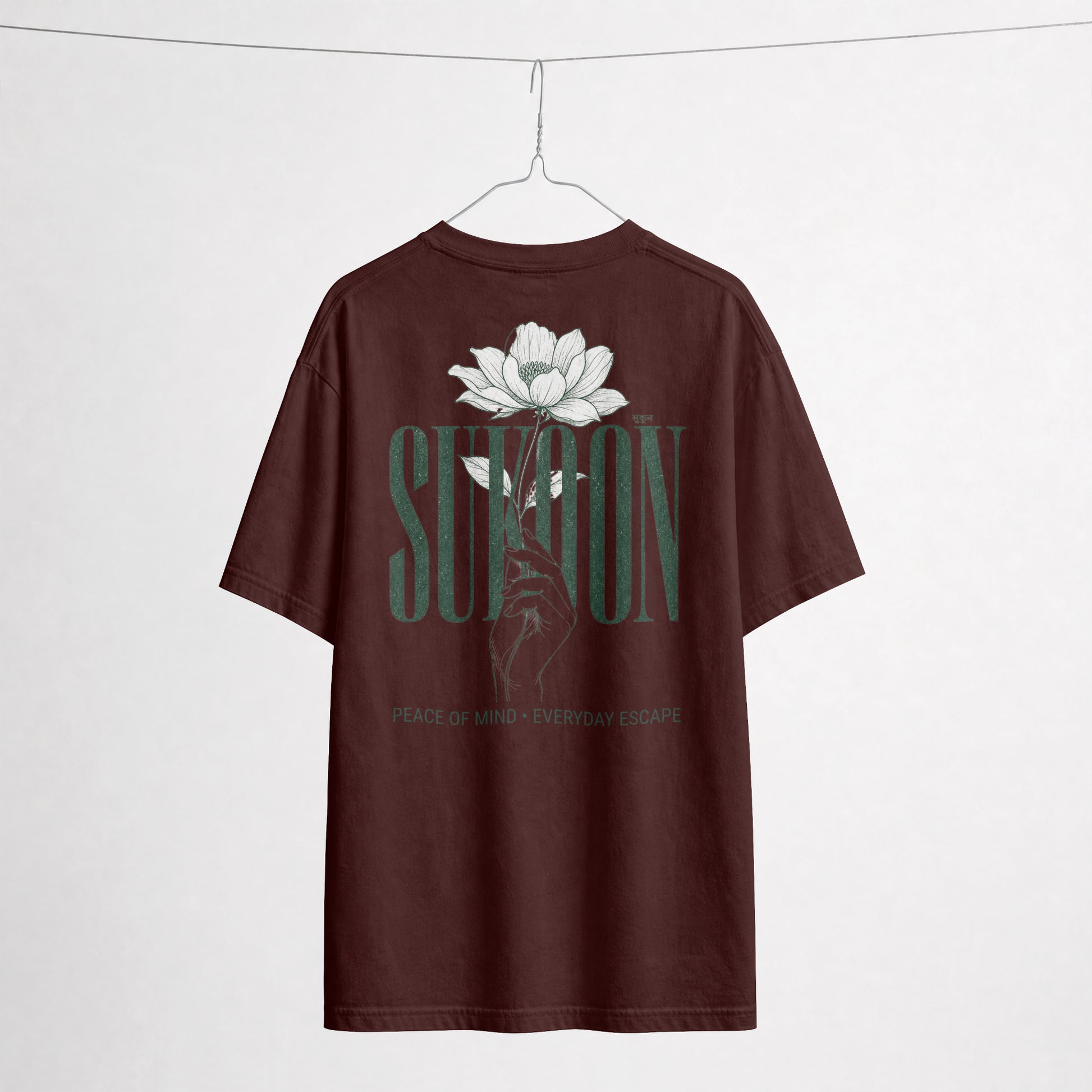Nauma Sukoon oversized t-shirt in maroon on a hanger, back print with lotus flower and hand illustration
