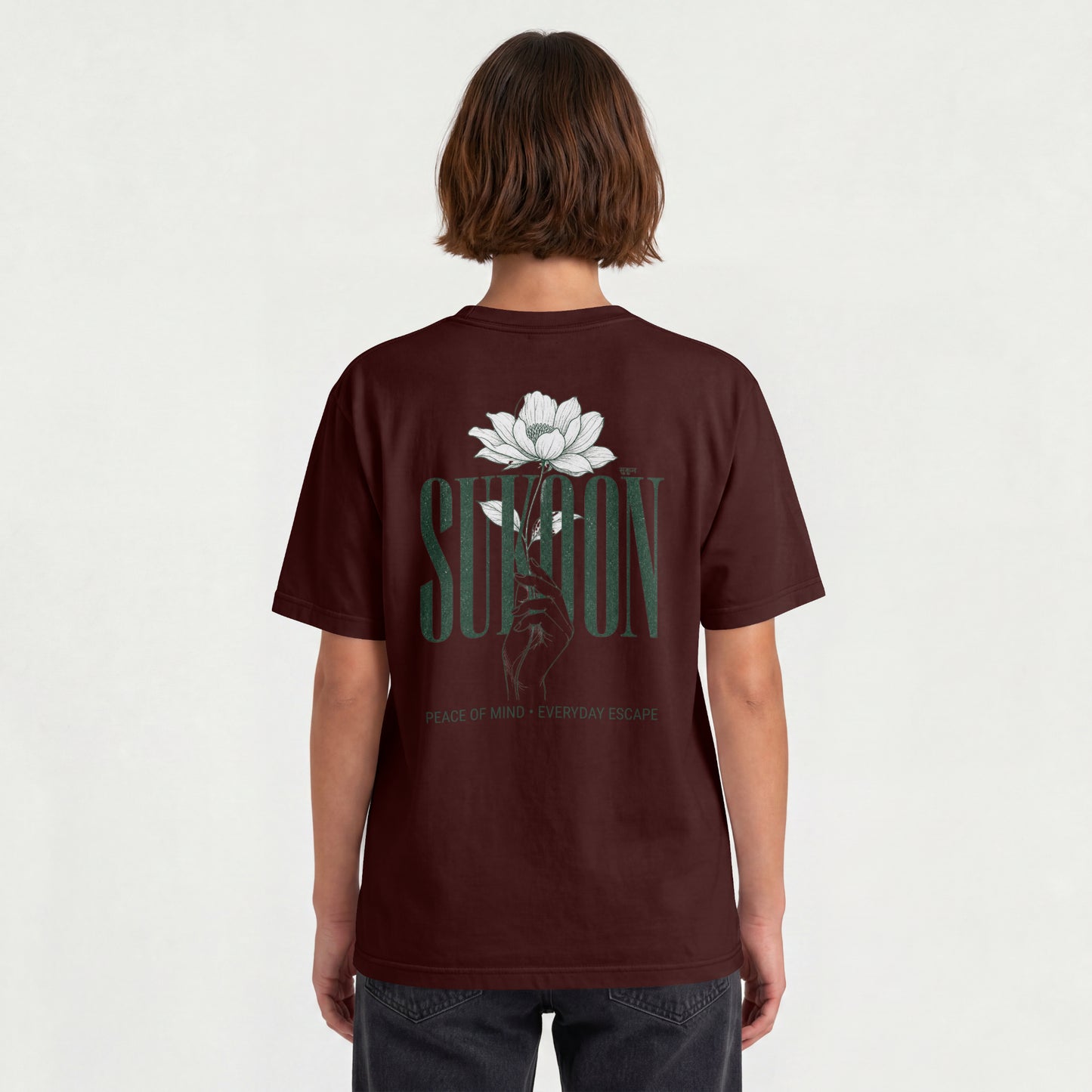 Model wearing Nauma Sukoon oversized t-shirt in maroon, back view showing lotus flower and hand print