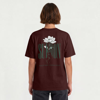 Model wearing Nauma Sukoon oversized t-shirt in maroon, back view showing lotus flower and hand print