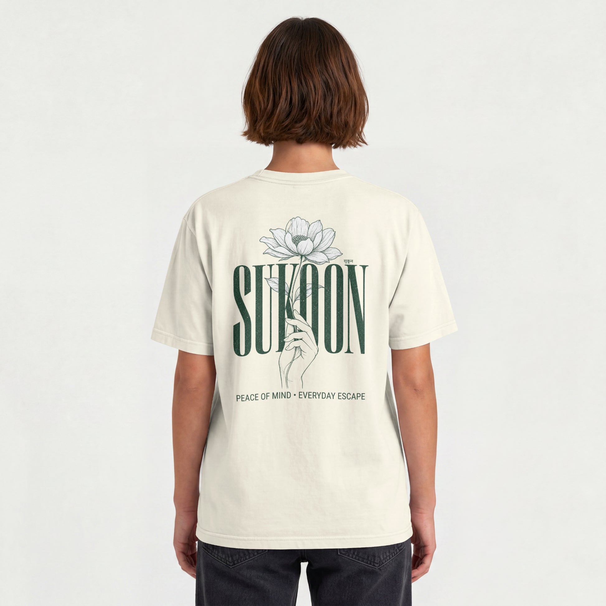 Model wearing Nauma Sukoon oversized t-shirt in off white, back view showing lotus flower and hand print