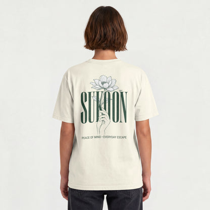 Model wearing Nauma Sukoon oversized t-shirt in off white, back view showing lotus flower and hand print