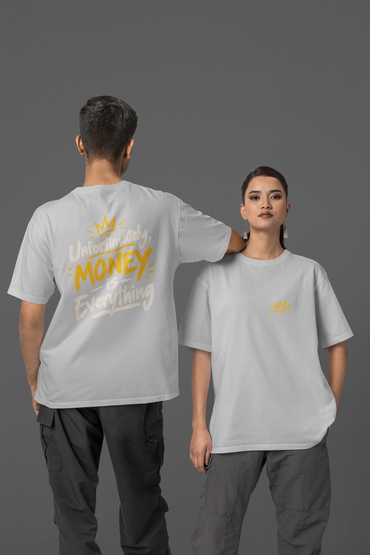 Melange Grey Unfortunately Money Is Everything oversized T-shirt on a man and woman, light back slogan print with MONEY in mustard yellow, small crown on the front chest