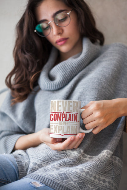 Woman in a winter sweater holding the Never Complain Never Explain 11oz ceramic coffee mug by Nauma