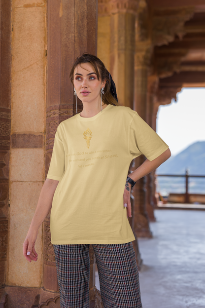Woman styling a beige baggy-fit drop-shoulder t-shirt with a gold torch print and inspirational message.