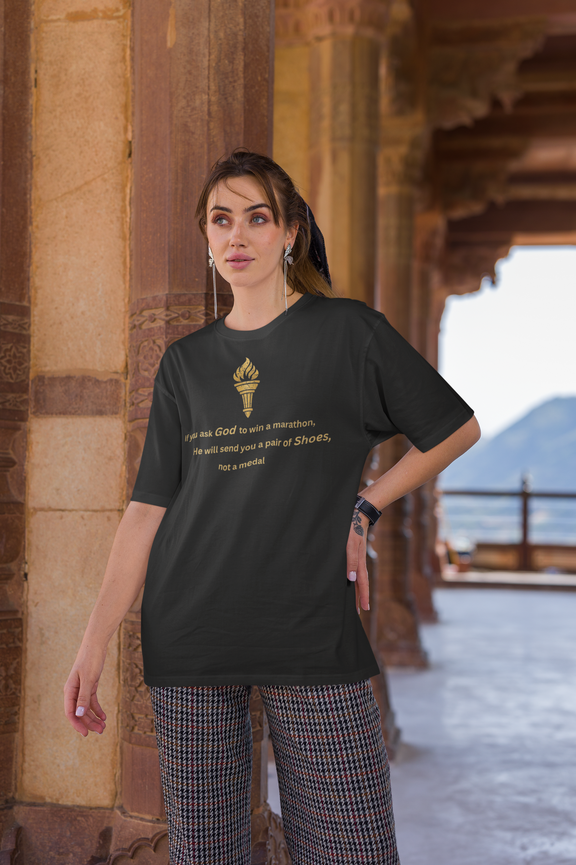 Woman styling a black baggy-fit drop-shoulder t-shirt with a gold torch print and inspirational message.