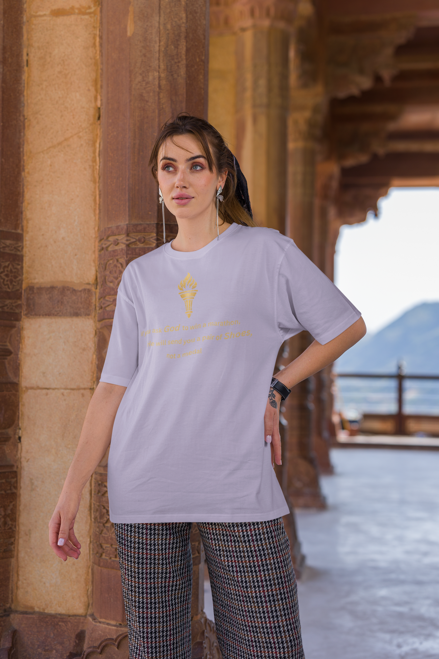 Woman styling a lavender baggy-fit drop-shoulder t-shirt with a gold torch print and inspirational message.