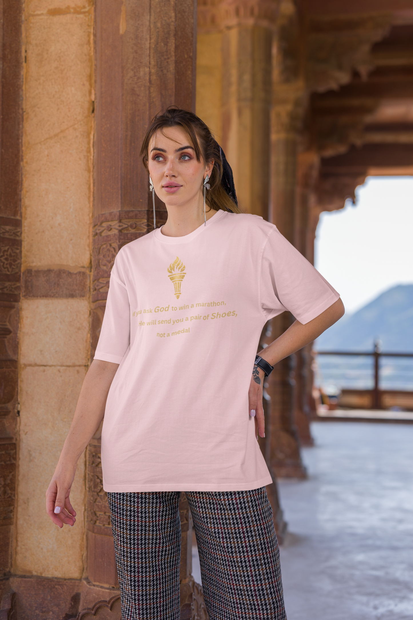 Woman styling a Baby light pink baggy-fit drop-shoulder t-shirt with a gold torch print and inspirational message.