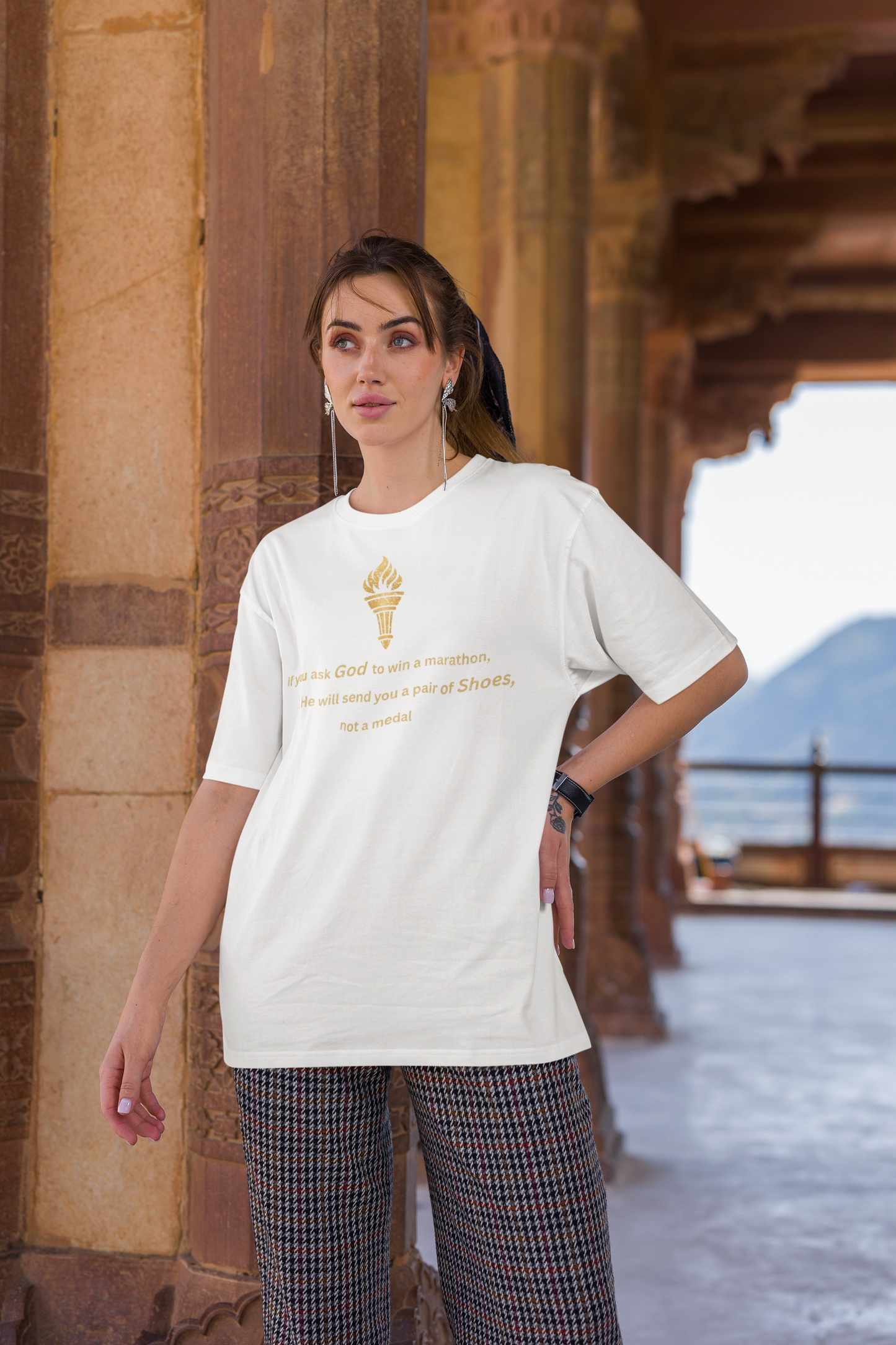 Woman styling a white baggy-fit drop-shoulder t-shirt with a gold torch print and inspirational message.